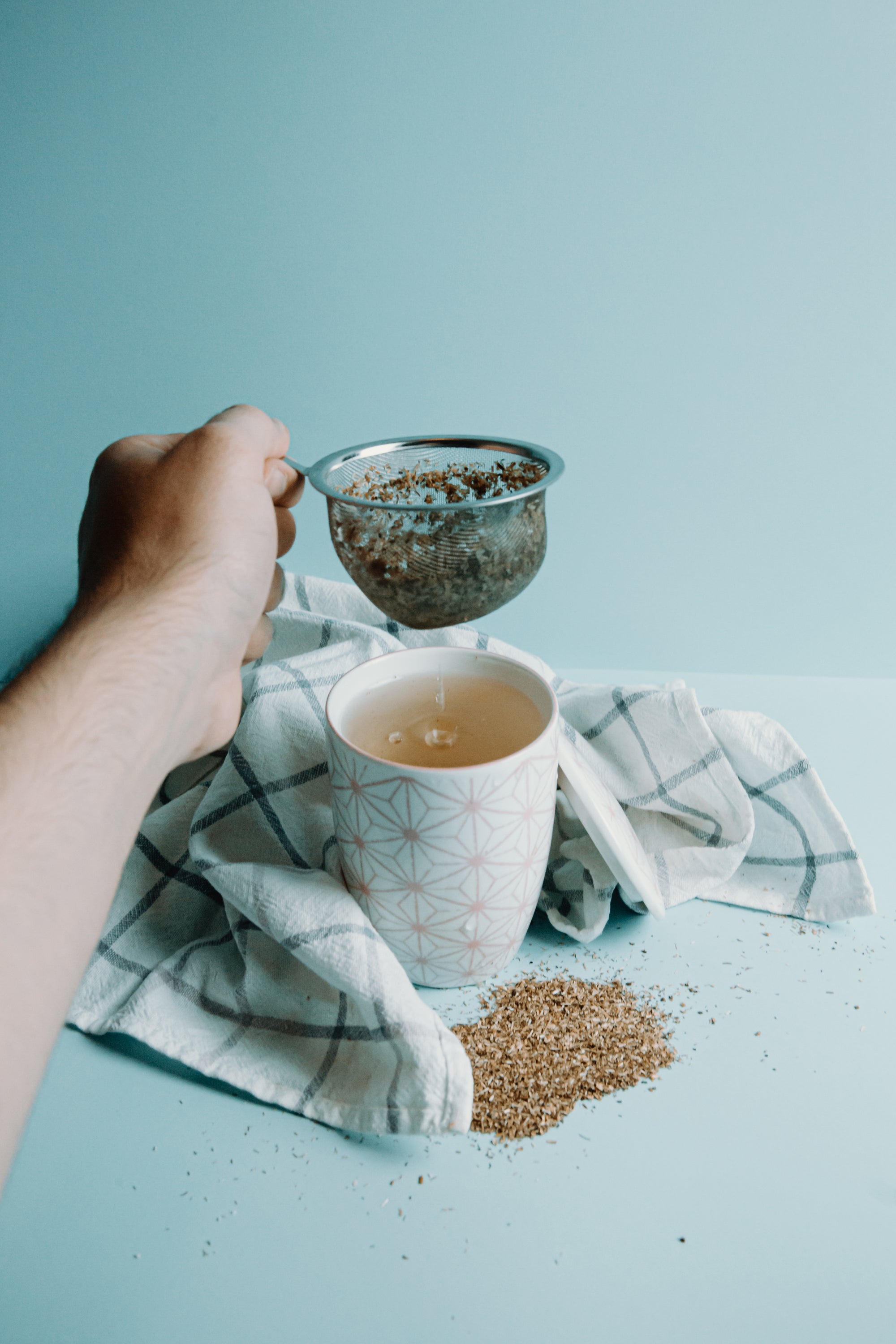 hand_holds_a_strainer_from_a_cup_of_tea