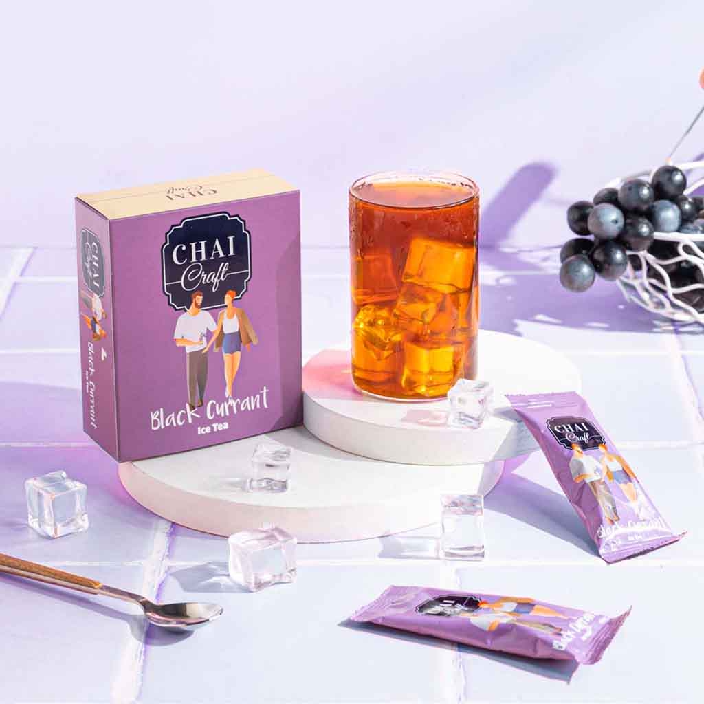 Chai Craft Blackcurrant Instant Ice Tea box with sachet, brewed tea in a glass, fruit and ice cubes